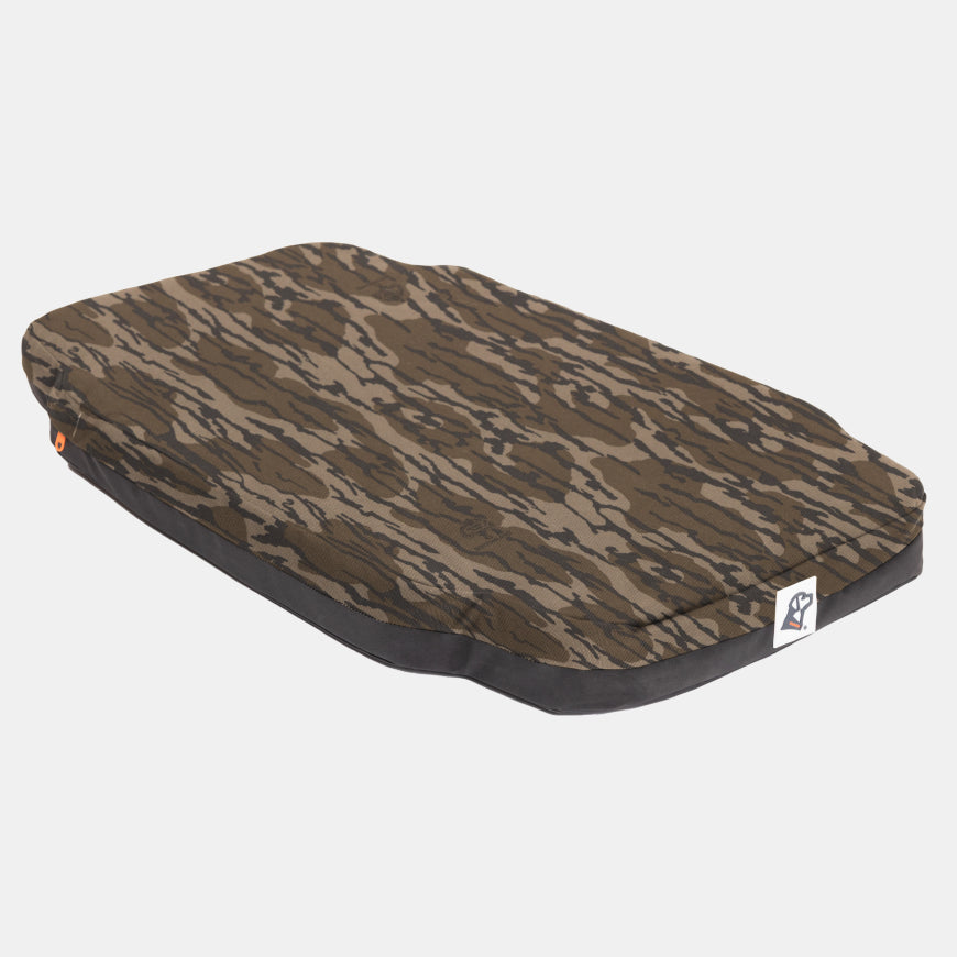 Rectangular dog bed with a brown and black camouflage-patterned cover, black sides, and a small white tag with a blue logo on one corner. Designed for use in a dog kennel or dog crate, this bed is shown on a plain white background.