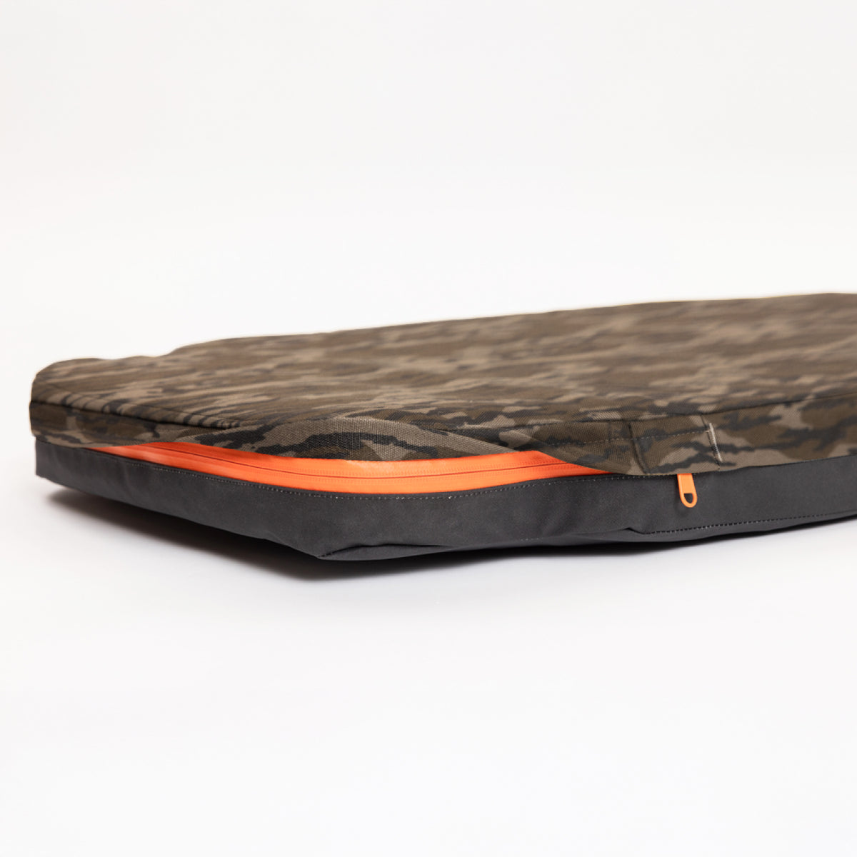A camouflage-patterned, zippered laptop sleeve with an orange zipper, reminiscent of the rugged gear used in a working dogs crate, lying flat on a white background.