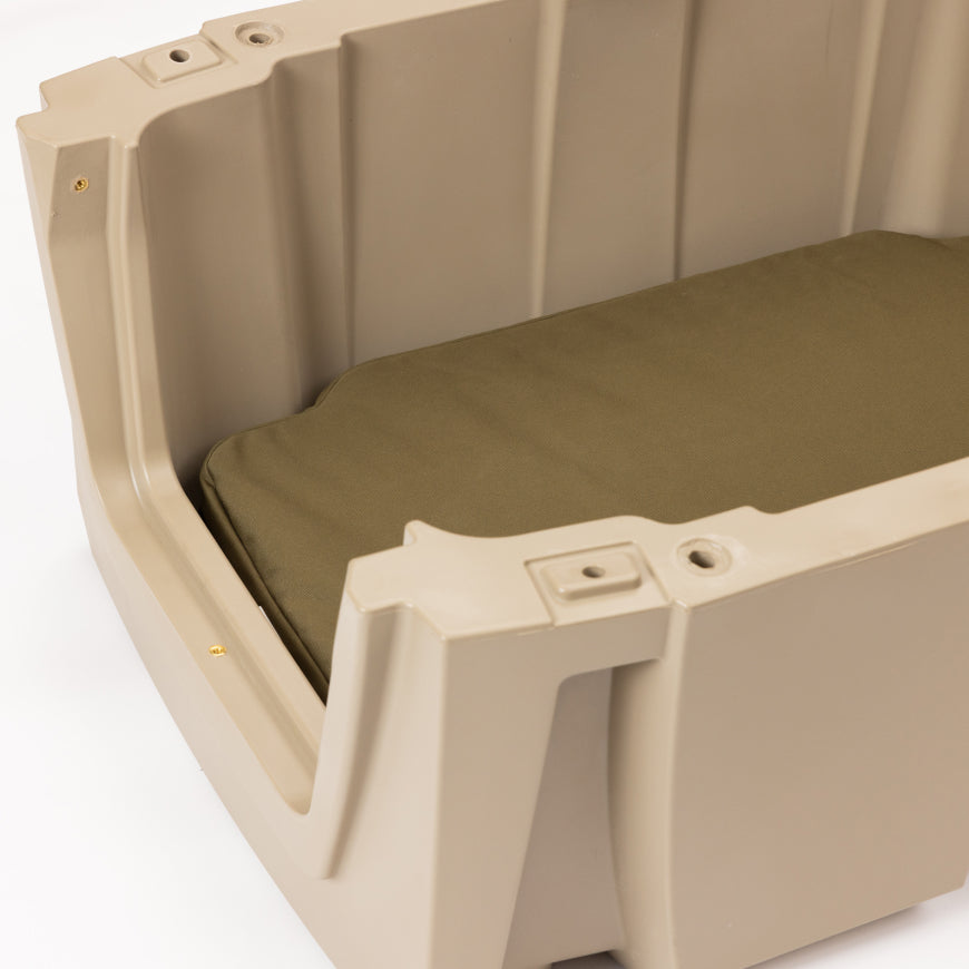 A close-up of a beige plastic dog crate with an olive green cushion inside, shown against a white background.