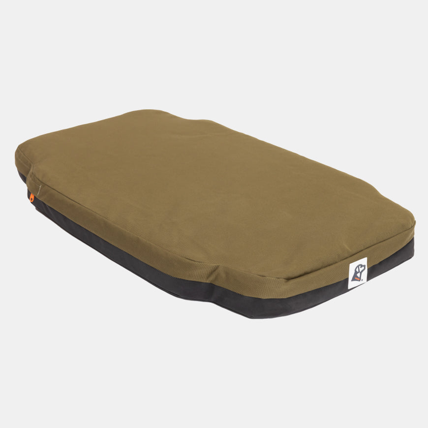 Olive green rectangular dog bed with a black base, lying on a white background. Perfect for use in a kennel or dog crate, this bed features a small white tag with a logo sewn onto one corner for added detail.