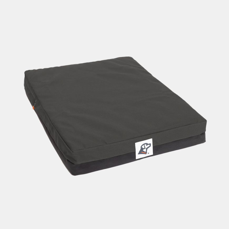 A rectangular black dog bed with a white logo tag on the front, perfect for use in a dog kennel, shown on a plain white background.