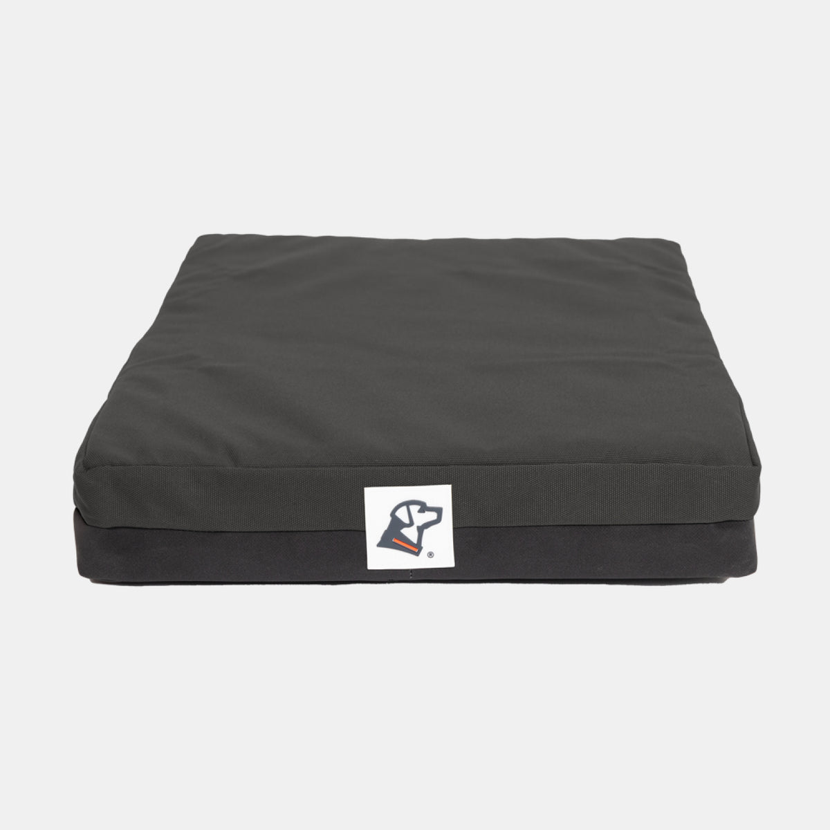 A square black dog bed with a small white logo featuring a dogs head on the front, set against a plain white background—perfect for adding comfort to your dogs kennel or complementing their outdoor gear.