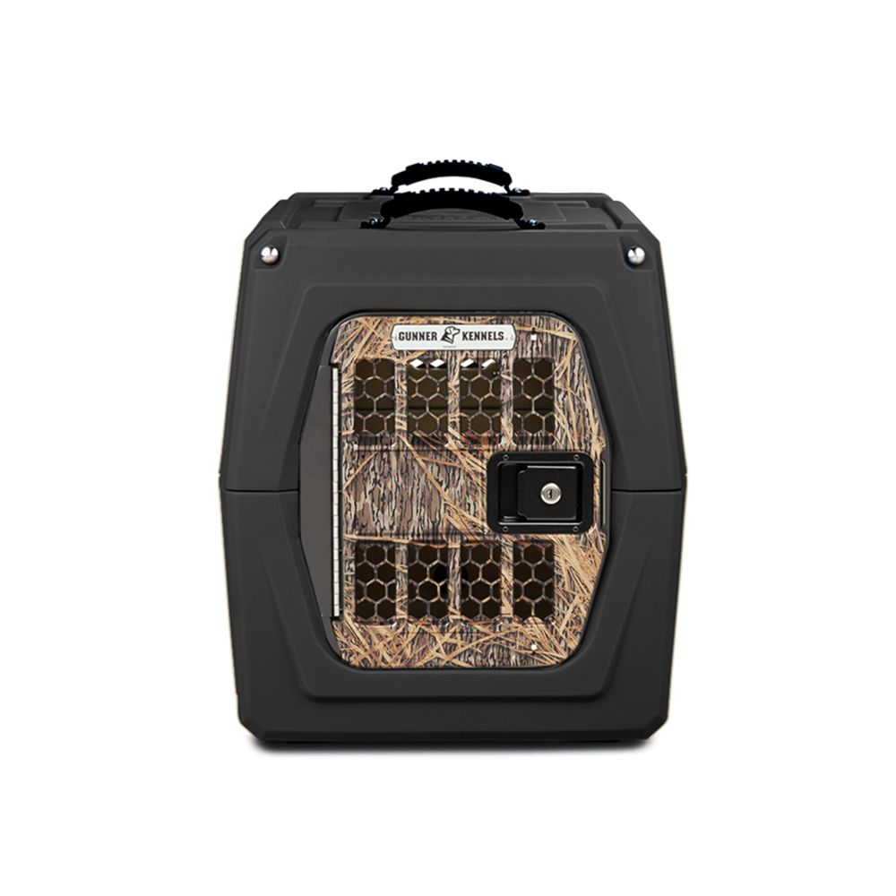 The GUNNER G1™ KENNEL - BLACK/SHADOW GRASS is a durable black dog crate with a camouflage metal door, ventilation holes, front latch, and top handle—engineered for safe and secure pet transport.