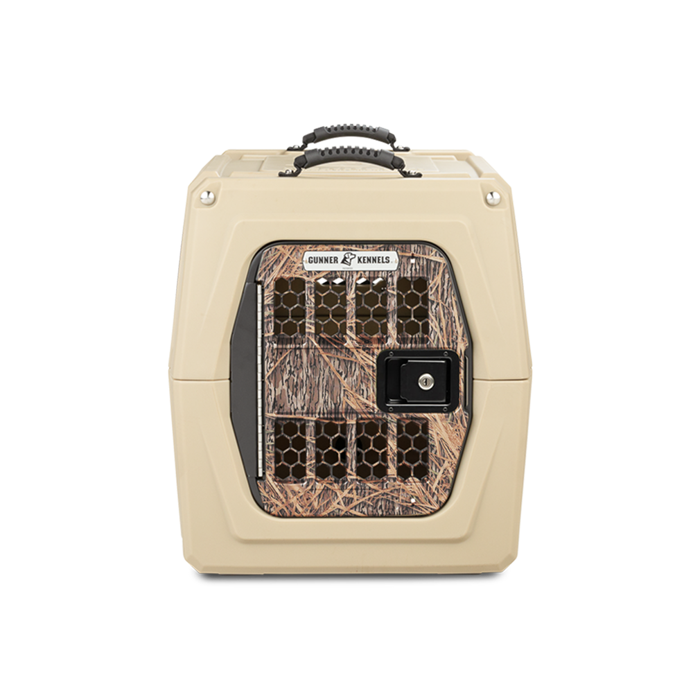 The GUNNER G1™ KENNEL - TAN/SHADOW GRASS features a black handle, front door in Shadow Grass camo, ventilation holes, sturdy latch, and Gunner branding—perfect for duck hunters wanting secure and stylish transport for their dogs.