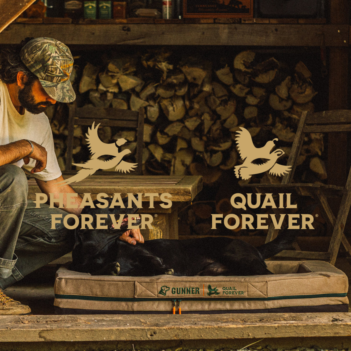 A man sits beside his hunting dog resting on a dog bed in a rustic wooden cabin. Firewood is stacked in the background, and outdoor gear can be seen nearby. Logos for Pheasants Forever and Quail Forever are overlaid on the image.