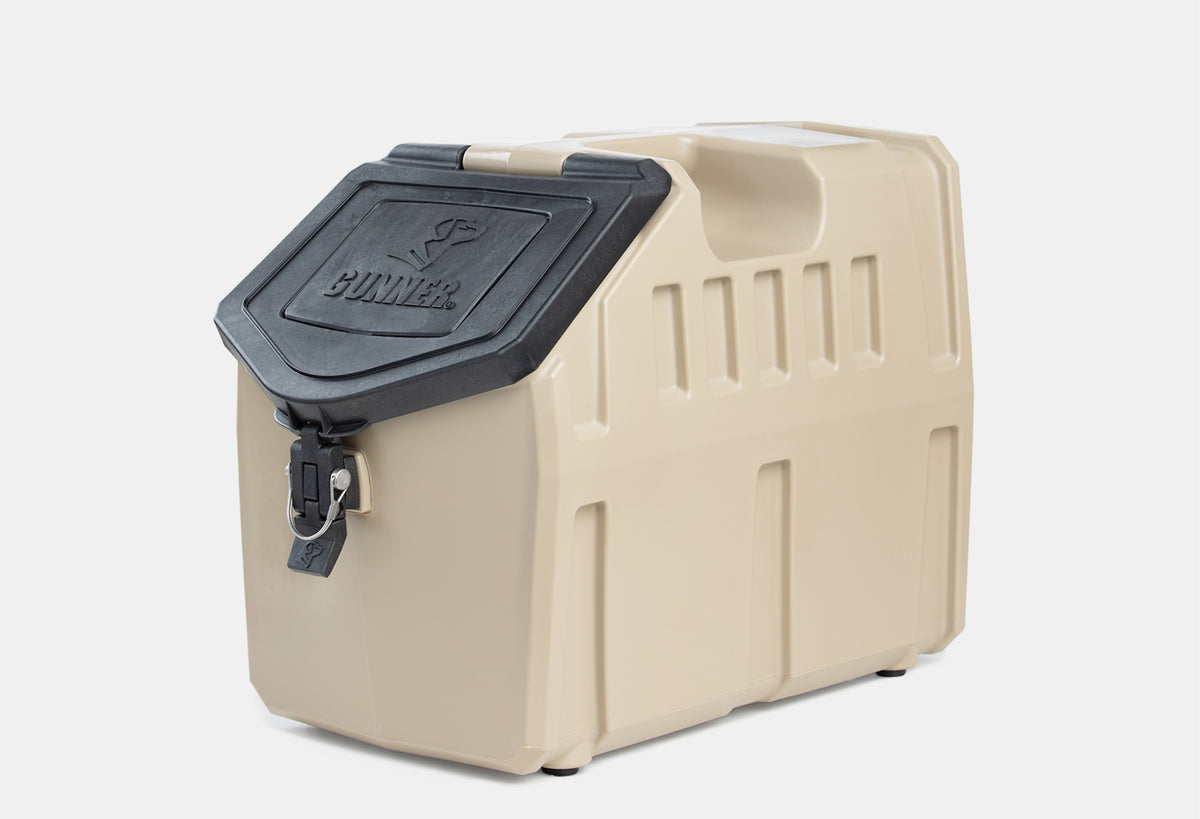 A tan, heavy-duty plastic storage container with a black lid labeled Gunner, featuring a secure latch and lock—perfect for storing outdoor gear or using as a portable dog crate thanks to its durability and portability.
