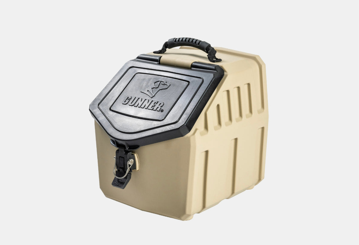 A tan, heavy-duty plastic storage container with a black, lockable lid and a sturdy handle on top—perfect for storing outdoor gear or dog crate accessories. The lid is embossed with the word GUNNER and a dog logo.