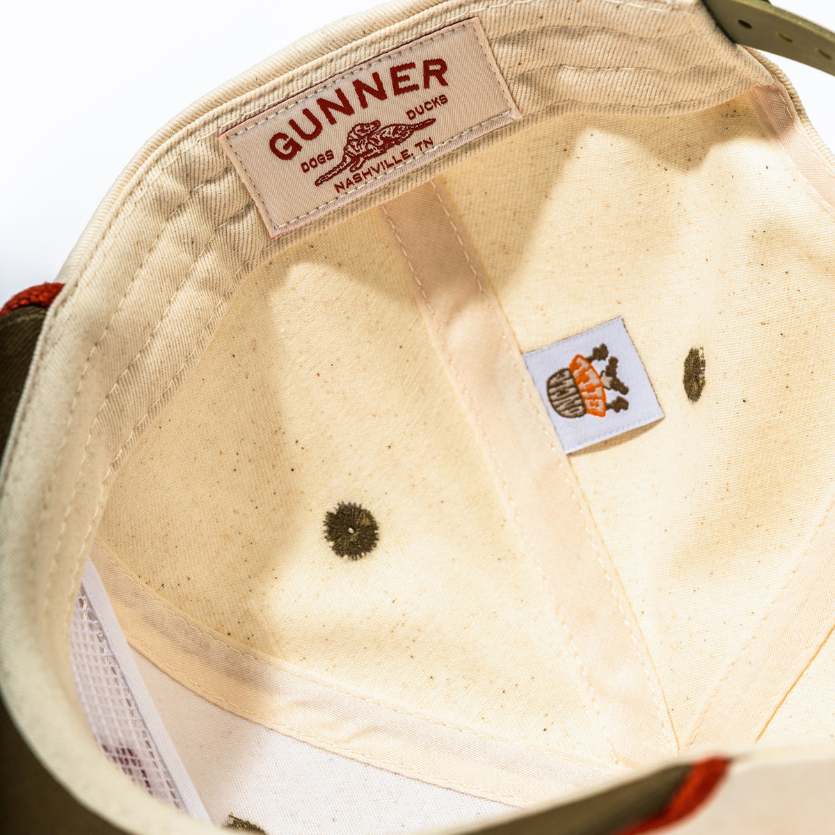 The D & D Rope Hat by GUNNER features a cream interior with a white GUNNER Dogs Ducks Nashville, TN label, a brown dog logo tag sewn inside, bold red stitching, and a rust-colored rope for added style.