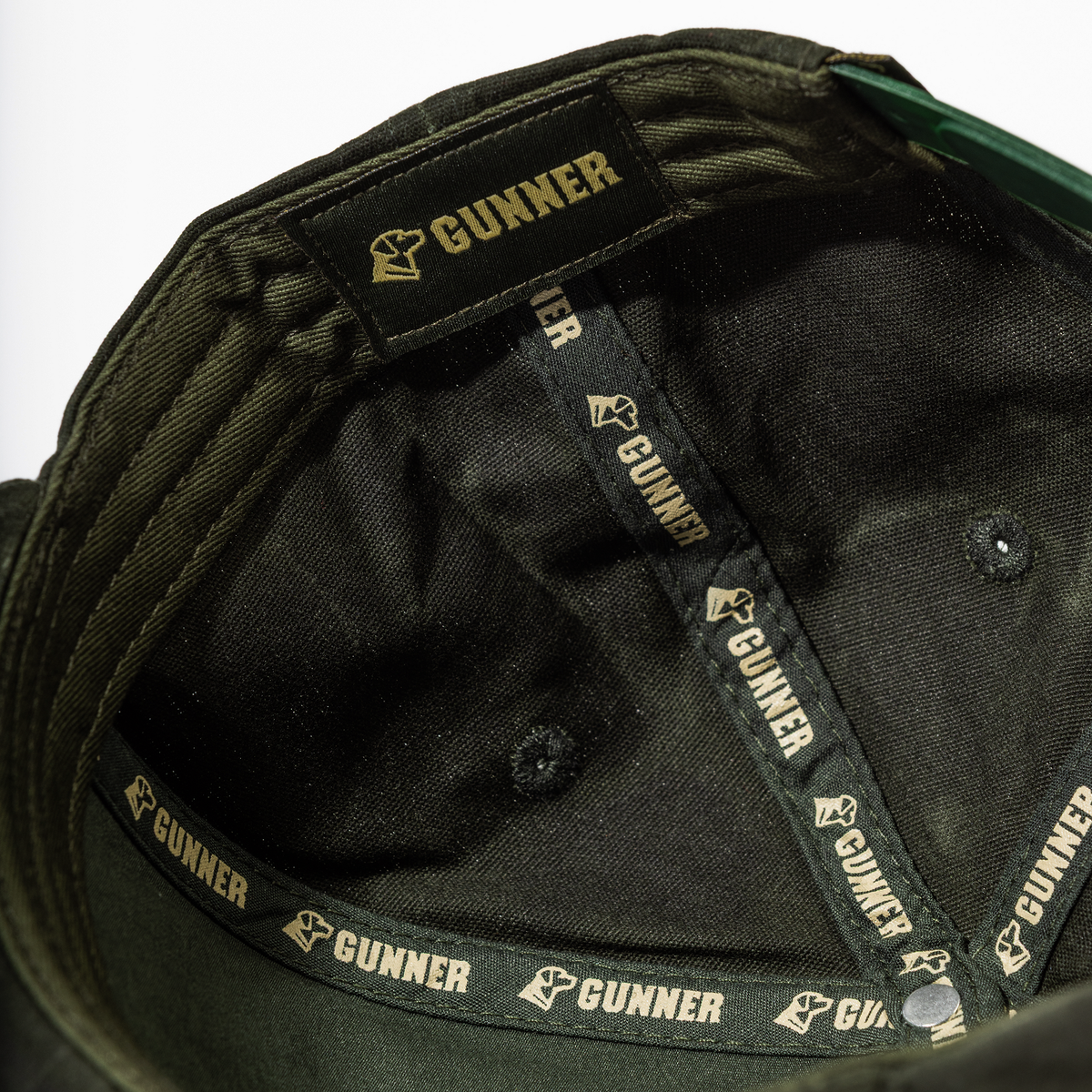 Close-up of the GUNNER Waxed Hat’s interior, featuring black fabric bands and tags with the GUNNER name and gold stylized fist logo—distinctive details that set this hat apart.