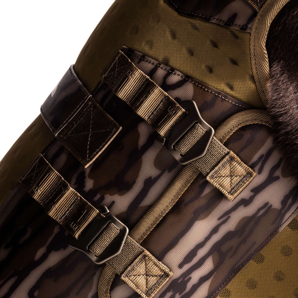 Close-up of Mossy Oak Bottomland® camo fabric with tan straps and black plastic buckles, part of the GUNNER Waterfowl Dog Vest, engineered with a 5-Layer Performance System for rugged outdoor use.