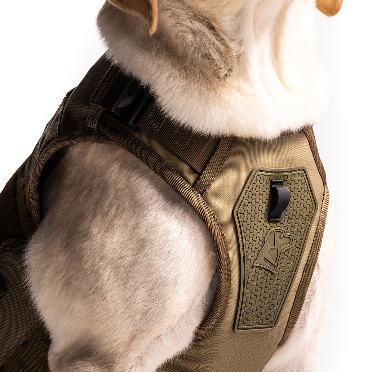 Close-up of a light-colored dog in the GUNNER Waterfowl Dog Vest Marsh featuring a 5-Layer Performance System, durable straps, handle, and a patch with a dog head logo and hexagonal pattern. The dogs head is partially out of frame.