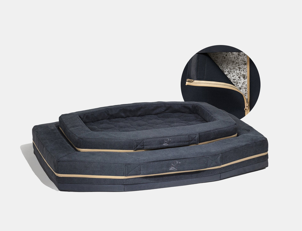 Two dark gray rectangular pet beds, one stacked on top of the other, with beige zippers. An inset shows a close-up of a zippered opening revealing inner stuffing—ideal comfort for your hardworking hunting dog or essential outdoor gear.