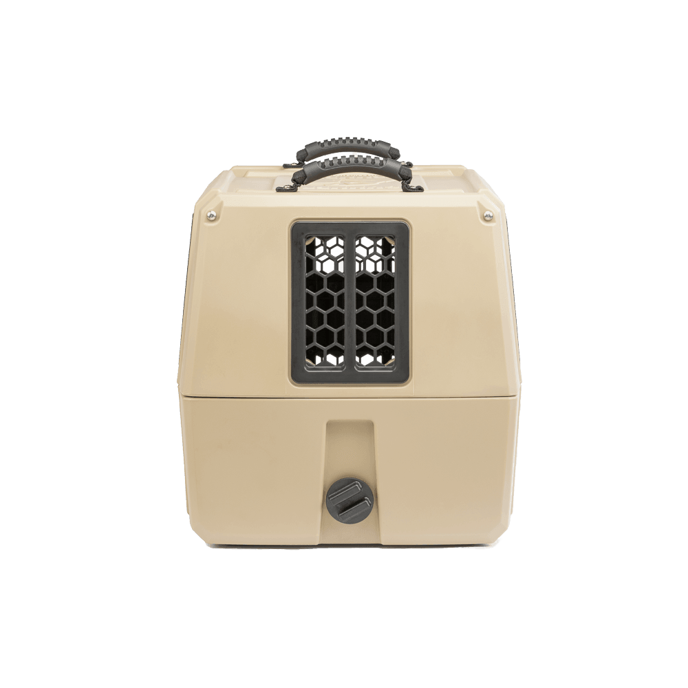 The GUNNER G1™ KENNEL - TAN is a beige, double-walled hard-shell pet crate with a black top handle, black front ventilation window, and twist-lock latch. Its designed for shock protection and is the safest dog crate for travel.