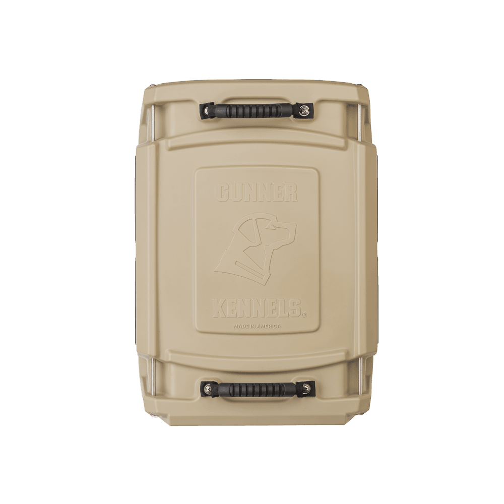 A tan G1™ KENNEL by GUNNER, shown from above with sturdy black handles and an embossed dogs head and GUNNER logo on the lid—double-walled design engineered for unmatched safety and superior shock protection for your dog.