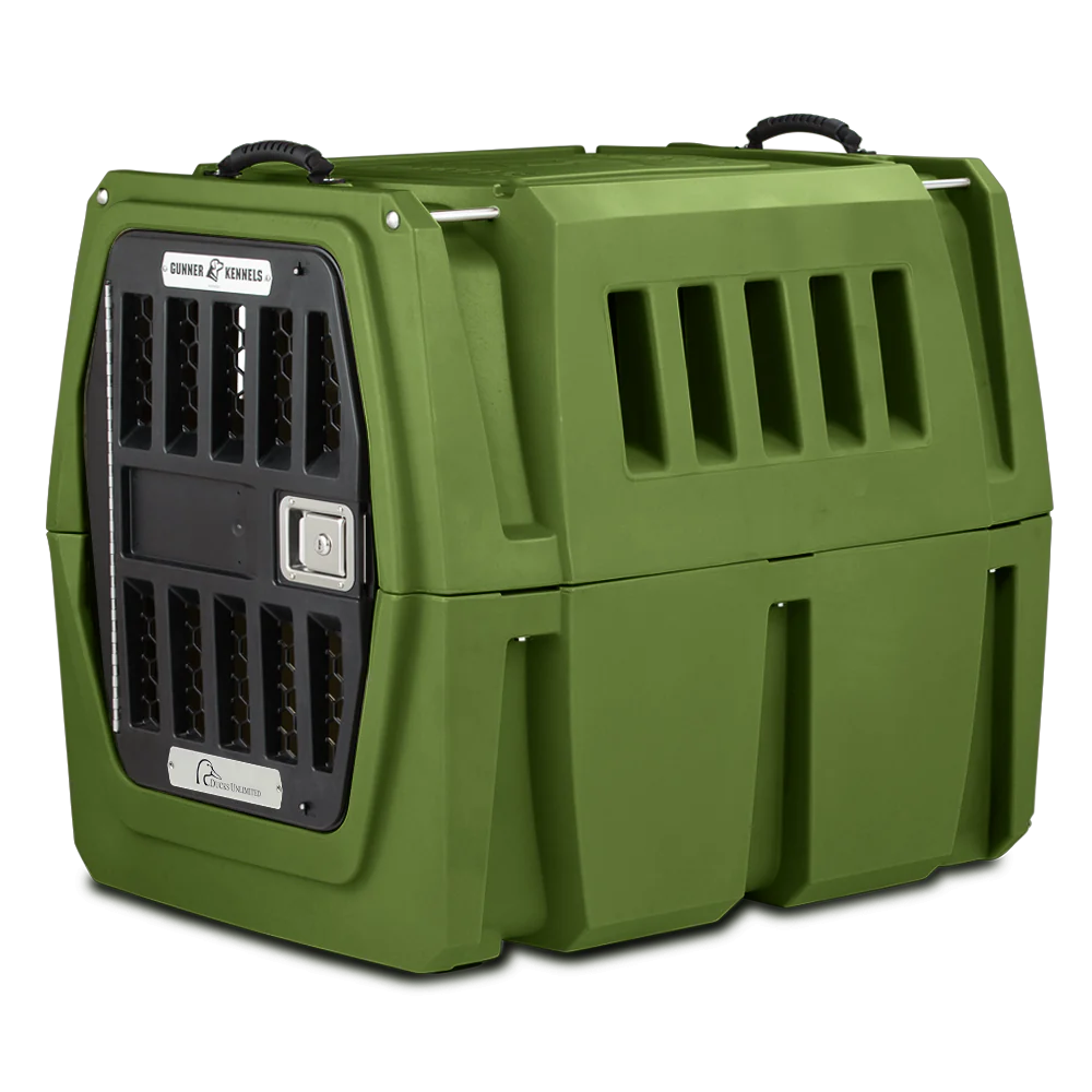 The GUNNER G1™ Kennel is a double-walled, olive green plastic dog crate with ventilation slats, a secure metal door, and top handles—providing shock protection and safe pet transport.