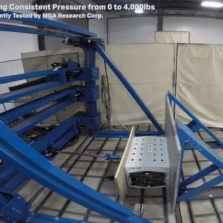 A mechanical testing machine presses a large residential safe against a metal frame, applying increasing pressure until the safe door bends and opens—much like rigorous tests for outdoor gear or a secure dog crate. Text at the top describes consistent pressure testing.