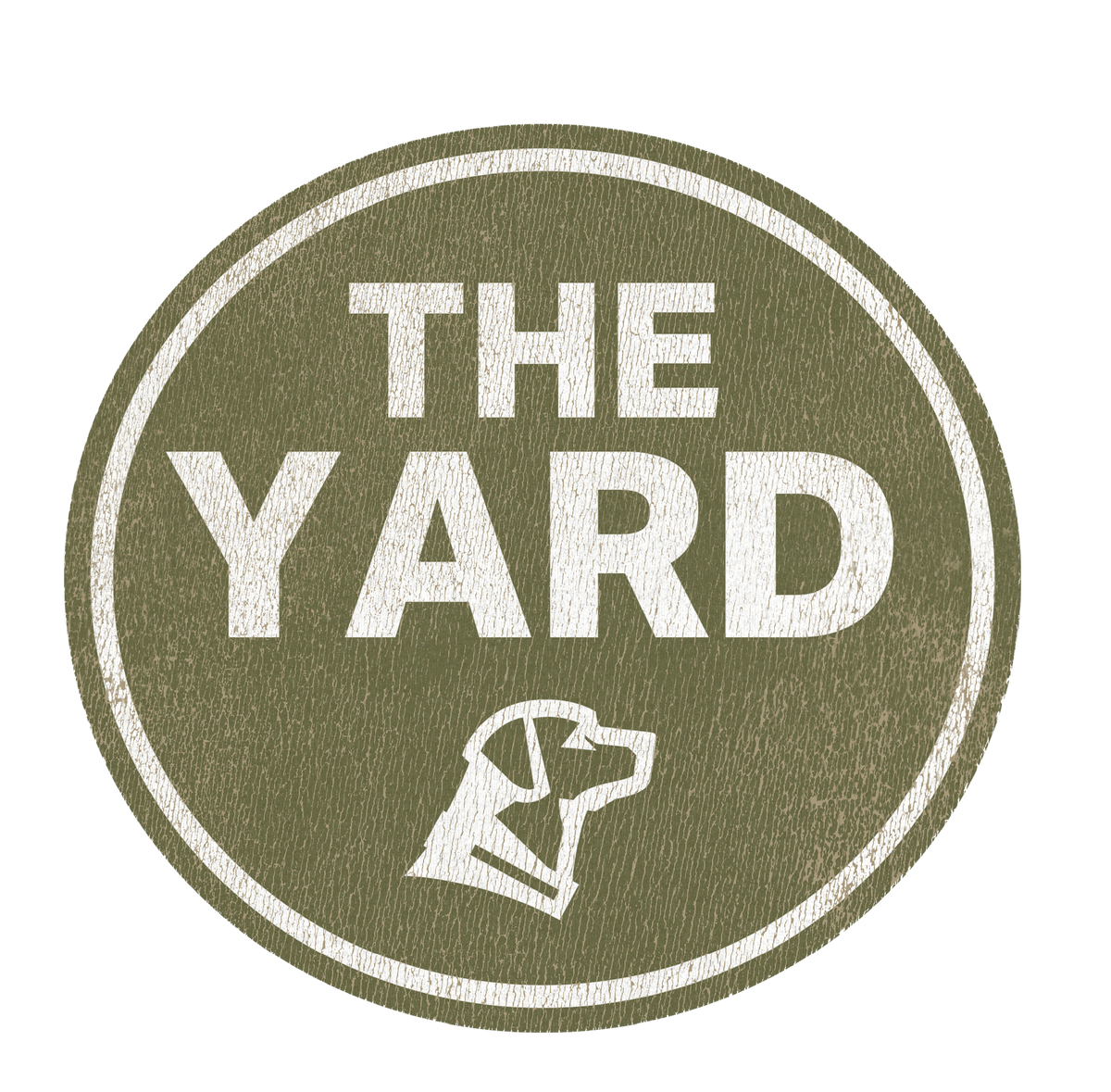 Green oval logo with white, textured letters reading THE YARD and a simple white outline drawing of a working dog’s head below the text. The design has a slightly worn, vintage appearance.