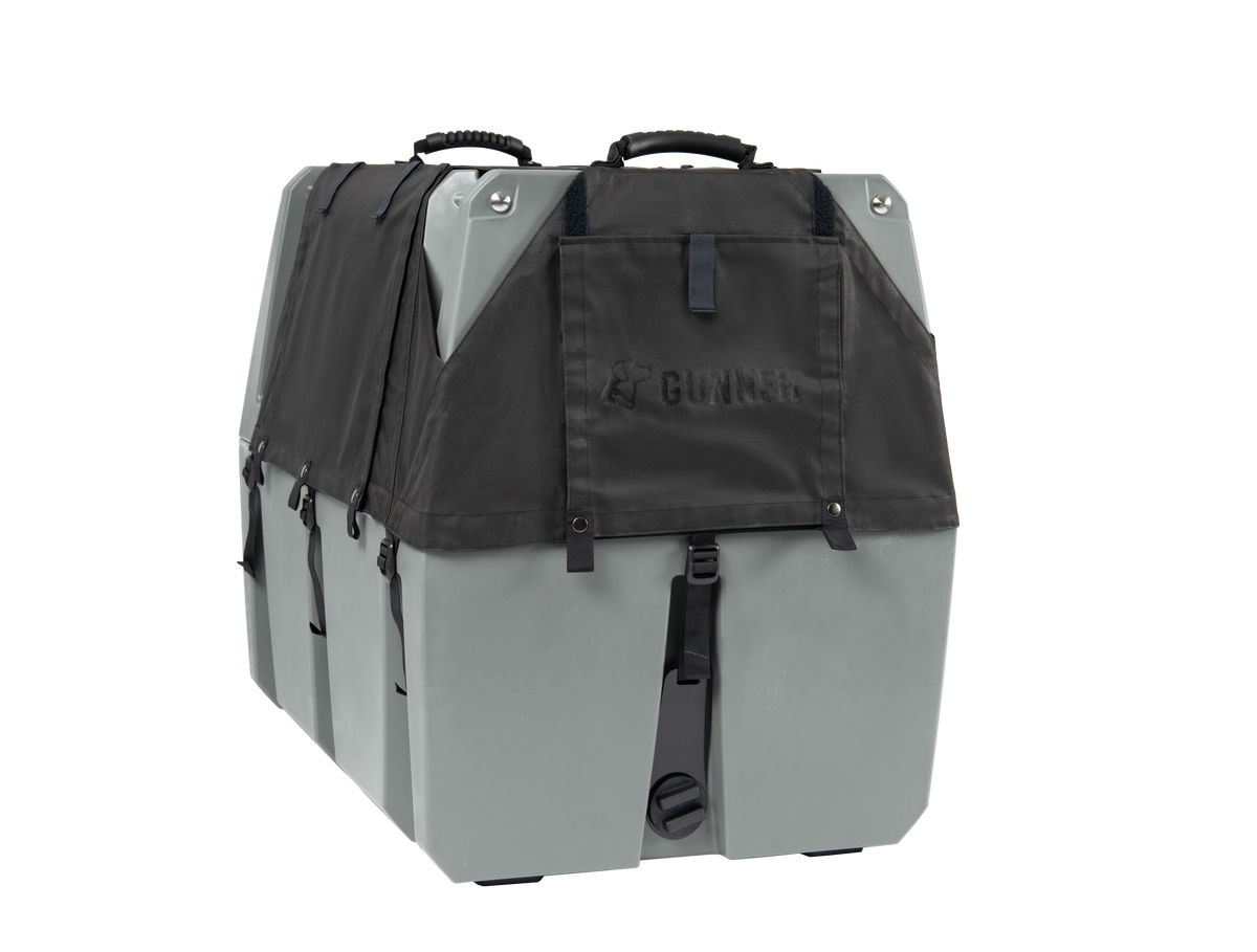 The GUNNER ALL-WEATHER KIT 2.0 is a sturdy gray hard-sided dog crate with a waterproof kennel cover, dual top handles, side ventilation slits, and metal hardware—an ideal wind-resistant dog accessory on a plain white background.