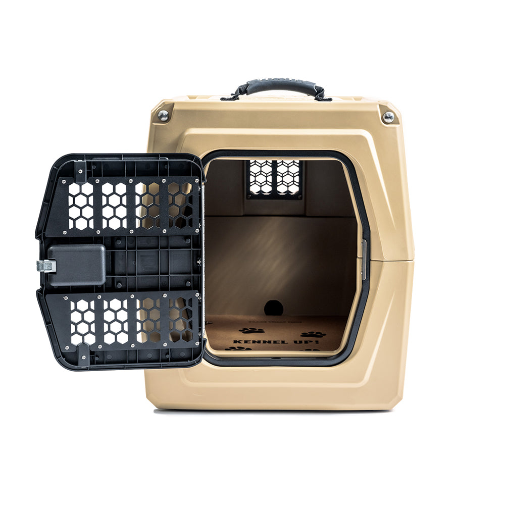The GUNNER CHEW KIT is a tan hard-sided pet crate with a black, hexagon-patterned left-opening door, top handle, ventilation holes, and interior paw prints for durable dog protection.