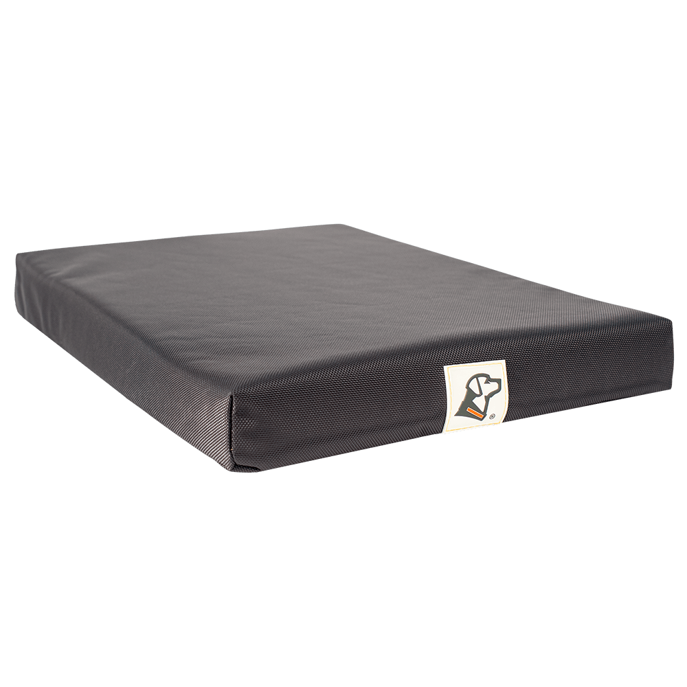The GUNNER ORTHOPEDIC KENNEL BED is a rectangular black ballistic nylon mat with a textured surface and a small dog head and bone logo tag on the front edge, shown against a plain white background.